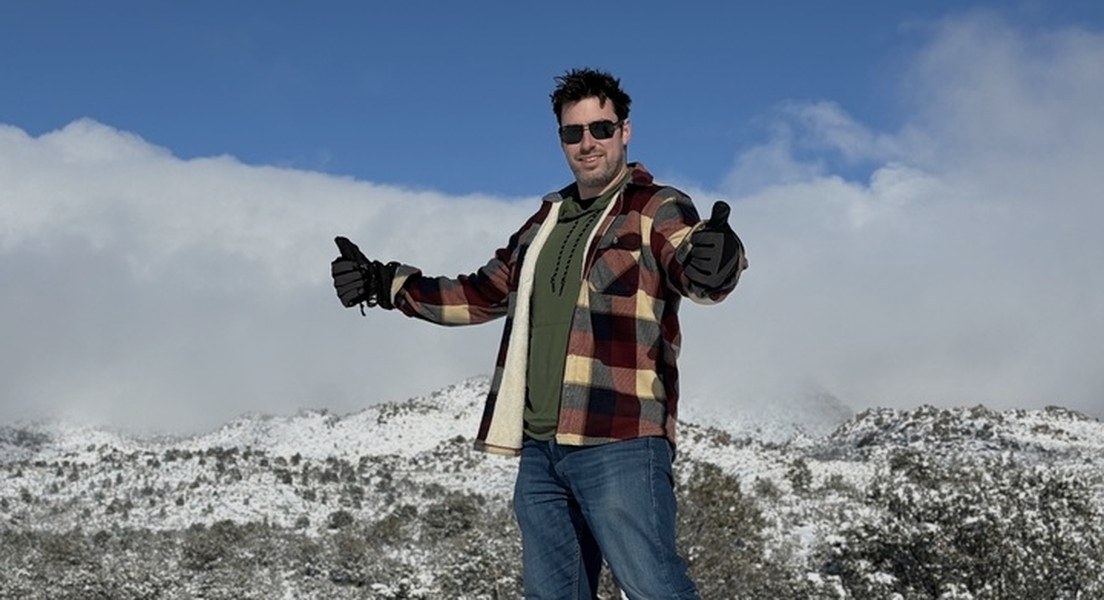 Travis Kempbell giving two thumbs up on a snowy mountain ridge