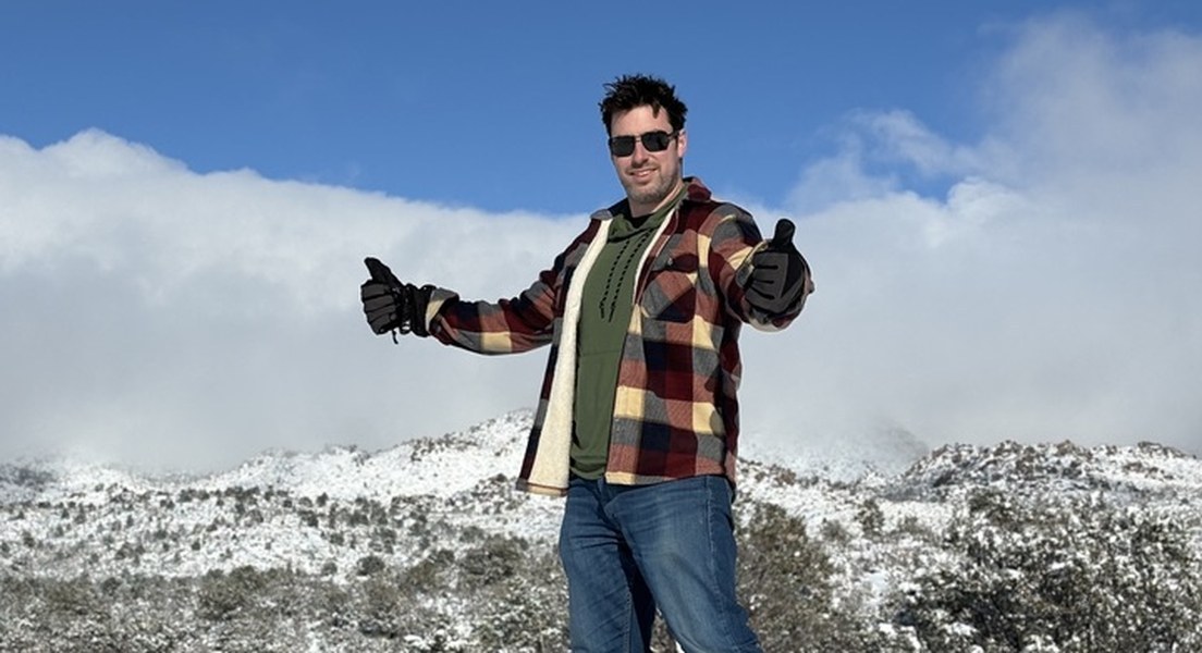 Travis Kempbell giving two thumbs up on a snowy mountain ridge